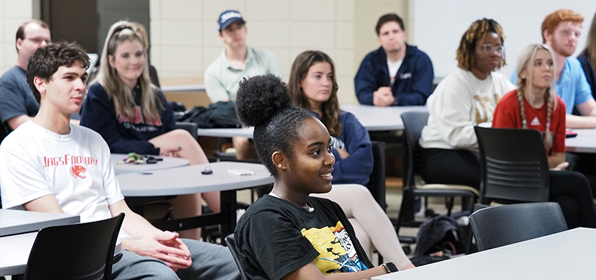 Communication students smiling listening in class.