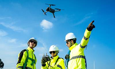 Three people on work site with drone.
