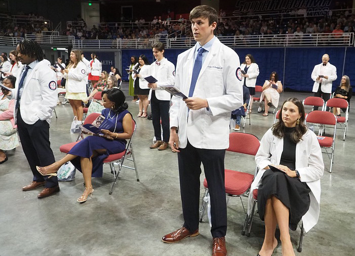 Students in white coats read oath