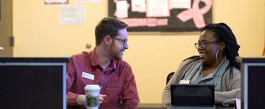 Two workers in Career Services talking at a desk.