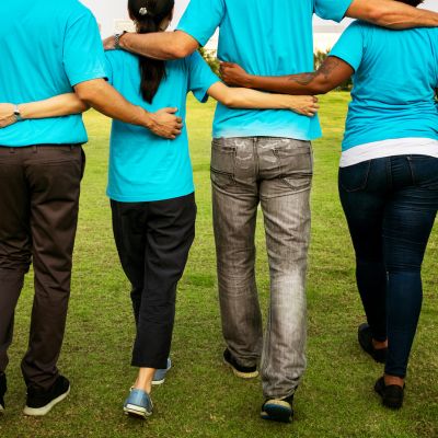 People working together with arms around each other from the back.