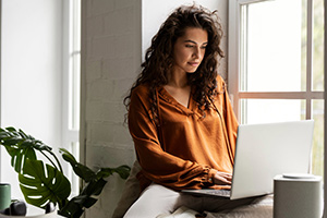 Woman working on laptop at table.
