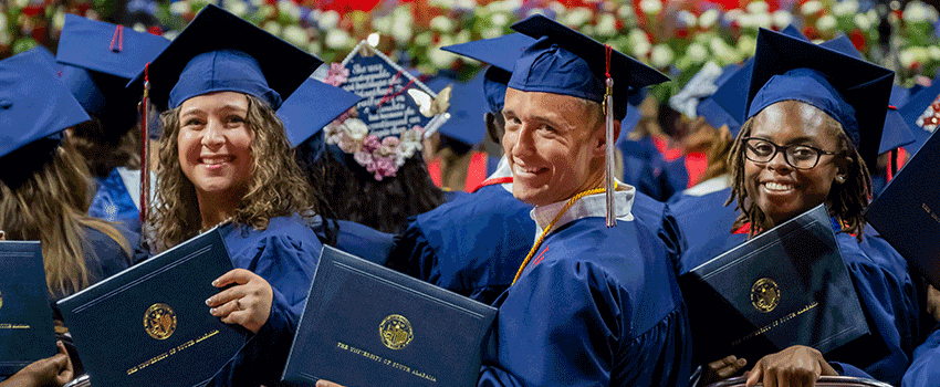 Graduate shaking hands on stage at graduation ceremony.